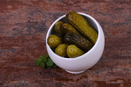 Pickled cucumbers heap in the bowl served basil leavesの写真素材