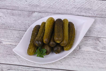 Pickled cucumbers heap in the bowl served basil leavesの写真素材