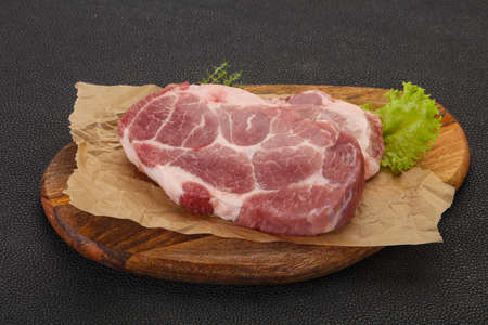 Raw pork steak over wooden board ready for cookingの写真素材