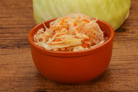 Pickled cabbage - sauerkraut in the bowl over woodenの写真素材