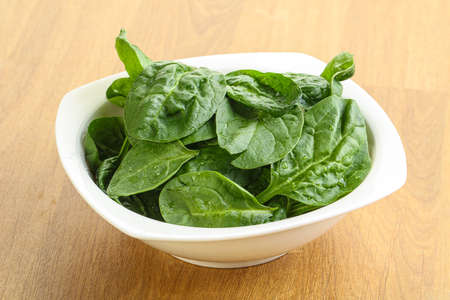 Fresh green spinach leaves in the bowl over wooden backgroundの写真素材