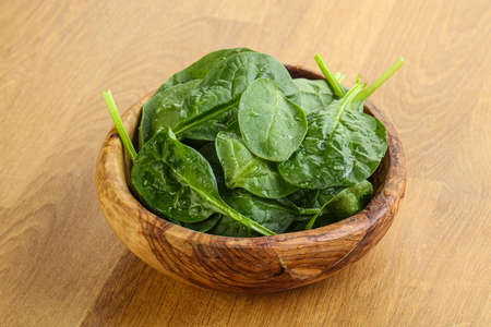 Fresh green spinach leaves in the bowl over wooden backgroundの写真素材