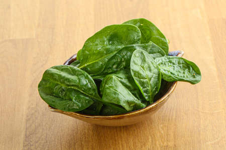 Fresh green spinach leaves in the bowl over wooden backgroundの写真素材