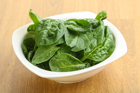 Fresh green spinach leaves in the bowl over wooden backgroundの写真素材