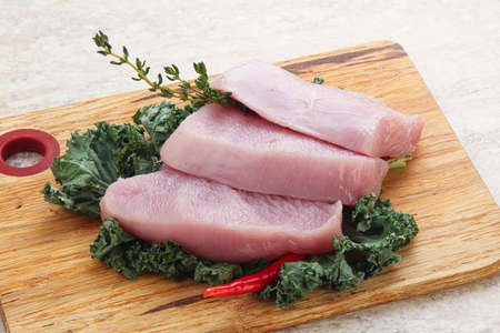 Raw turkey steak for grill over board with thymeの写真素材