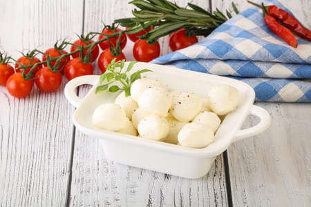 Mozzarella cheese balls in the bowl served basil leavesの写真素材
