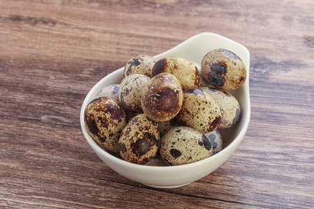 Quail eggs in a bowl on wooden background. Health food.の写真素材