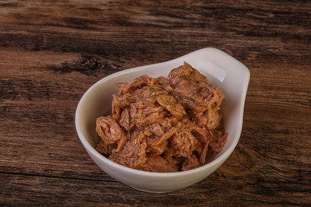 Canned tuna fish in the bowl over wooden background, top viewの写真素材