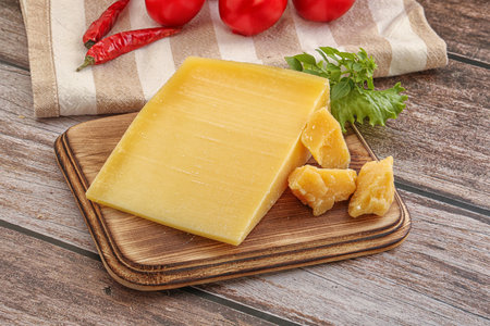 Parmesan cheese on a wooden cutting board with parsley and tomatoesの写真素材