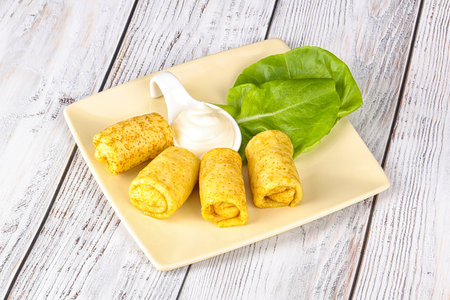 Pancakes stuffed with cheese, lettuce and sour cream on a plateの写真素材
