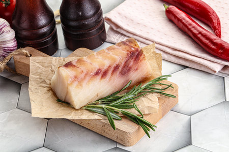 Raw cod fish fillet on wooden cutting board with rosemary and pepperの写真素材