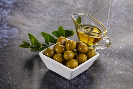 Ripe tasty green olives with branch and oilの写真素材