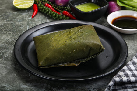 Asian cuisine - rice with filling wrapped in banana leafの写真素材