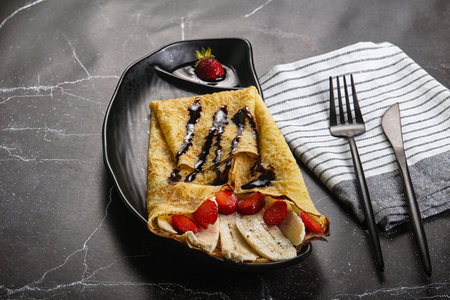 Sweet pancake with banana and strawbeery served chocolate toppingの写真素材