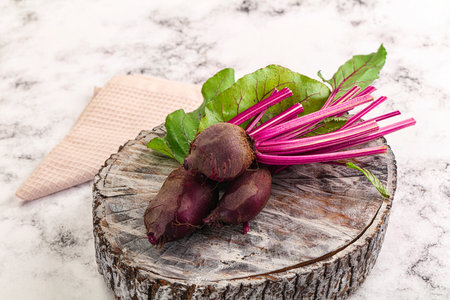 Young red fresh beetroot with leaves over board