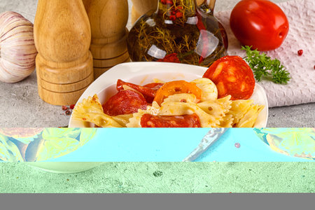 Italian pasta farfalle with pepperoni sausages and tomatoの写真素材