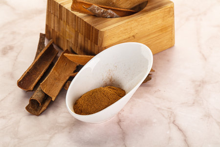 Natural Cinnamon powder in the bowl with sticks