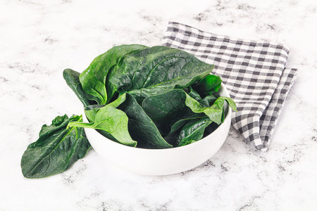 Ripe green spinach leaves heap in the bowlの写真素材