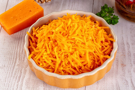 Yellow shredded natural cheddar cheese in the bowl