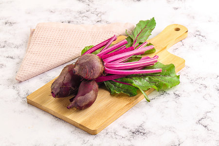 Young red fresh beetroot with leaves over board