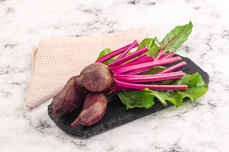 Young red fresh beetroot with leaves over board