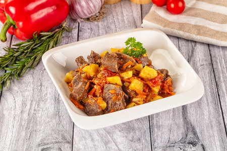 Beef stew with potatoes and vegetables in white bowl on wooden backgroundの写真素材