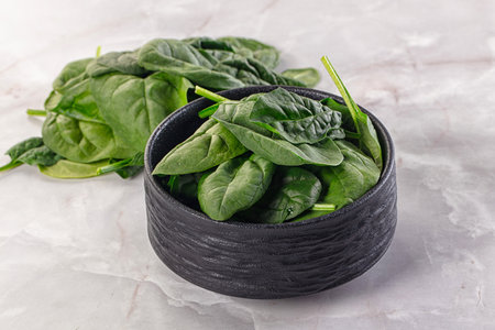 Raw green baby spinach plant in the bowlの写真素材