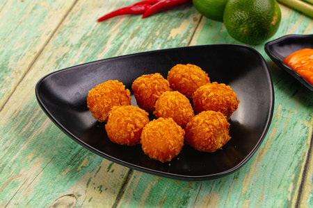 Fried crispy yellow cheese balls with sauce