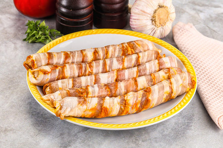 Raw sausages wrapped in bacon for grillの写真素材