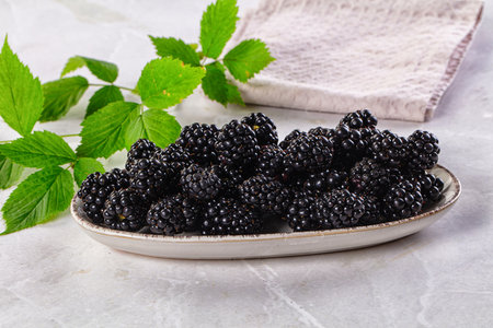 Raw sweet juicy blackberry in the bowl served leaves