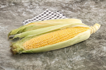 Ripe sweet yellow corn cob with leaves