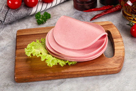 Sliced boiled sausage heap over board