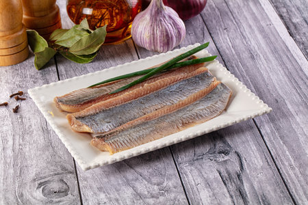Marinated salted herring fillet slices in the plate