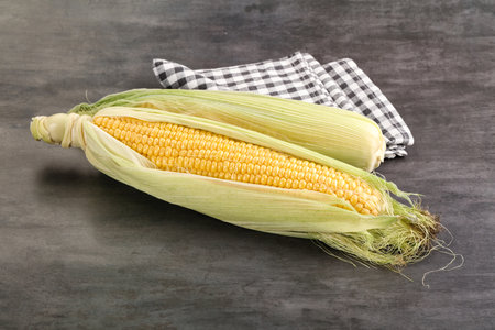 Ripe sweet yellow corn cob with leaves