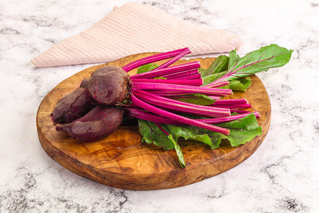 Young red fresh beetroot with leaves over board