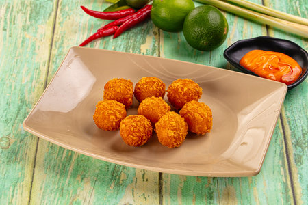 Fried crispy yellow cheese balls with sauce