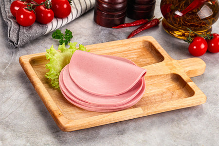 Sliced boiled sausage heap over board