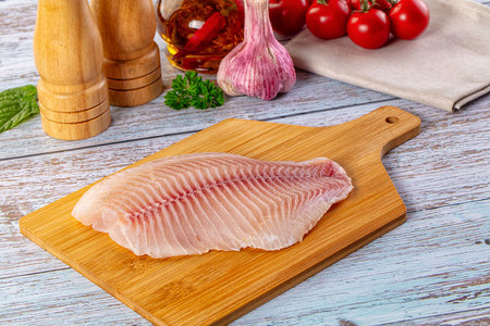 Raw tilapia fish fillet over board for cooking