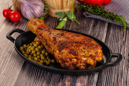Baked big turkey drumstick leg served green peasの写真素材