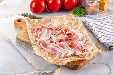 Sliced smoked pork bacon over boardの写真素材