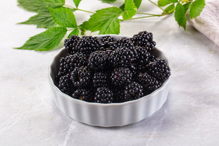 Raw sweet juicy blackberry in the bowl served leaves