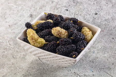 Ripe sweet juicy black and white mullberry in th the bowlの写真素材