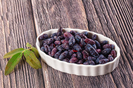 Sweet juicy ripe honeysuckle berries in the bowlの写真素材