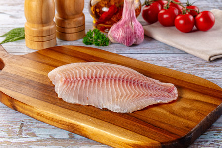Raw tilapia fish fillet over board for cookingの写真素材