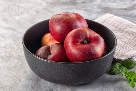 Ripe sweet juicy flat nectarines in the bowlの写真素材