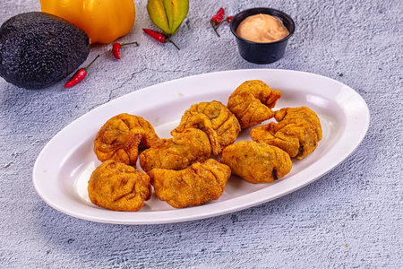 Golden deep-fried Tibetian Momo dumplings on a plate with a creamy dipping sauce. Fresh avocado,...