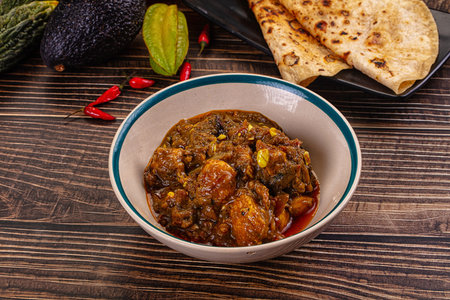 A delicious, authentic chicken curma curry dish served in a ceramic bowl with roti bread on the...