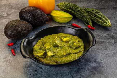 Vibrant bowl of green Palak Paneer, an Indian spinach and cheese curry. High-angle view on a dark...