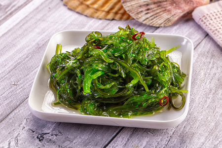 Appetizing Japanese seaweed salad, Chuka, with sesame and chili in a white bowl. Healthy green...