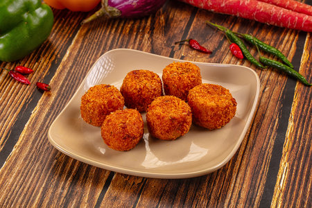 Top-down view of crispy golden-brown fried cheese and vegetable balls, a savory appetizer, on a...